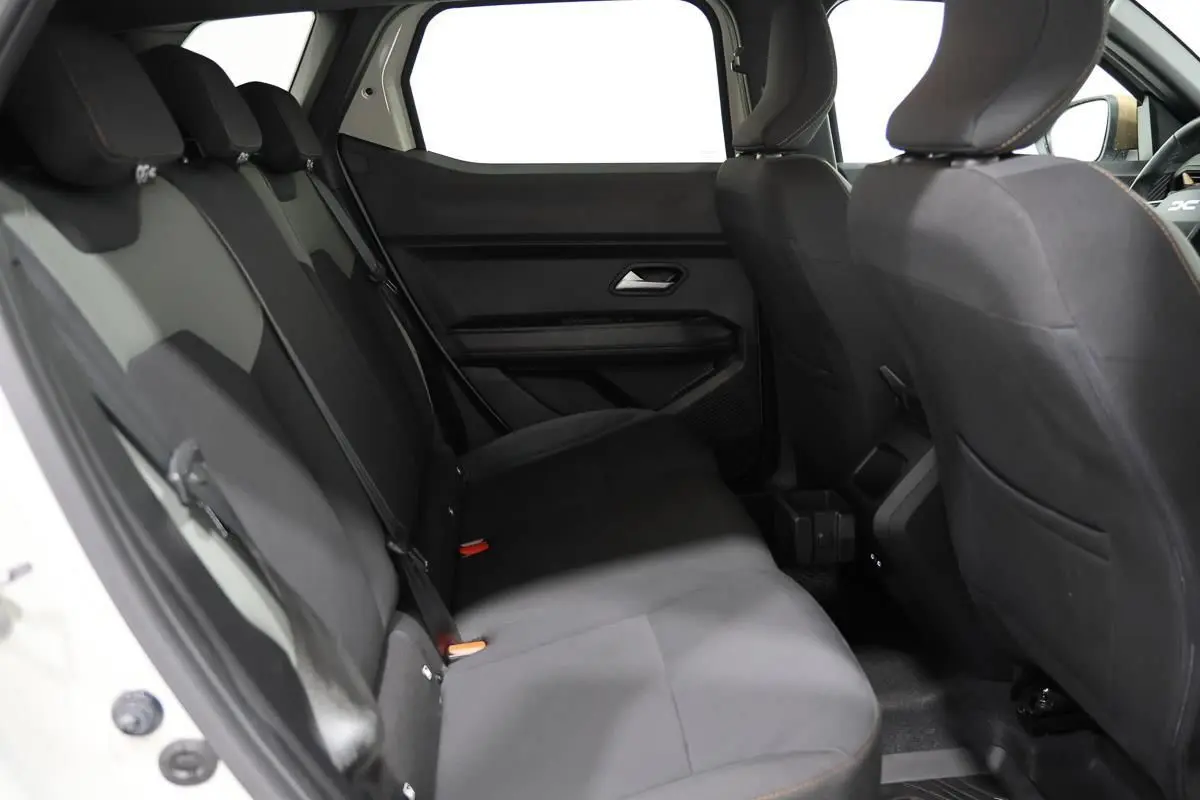 Vue intérieure arrière du Dacia Duster 2024, sièges tissu noirs avec surpiqûres contrastantes, habitacle spacieux et sobre.