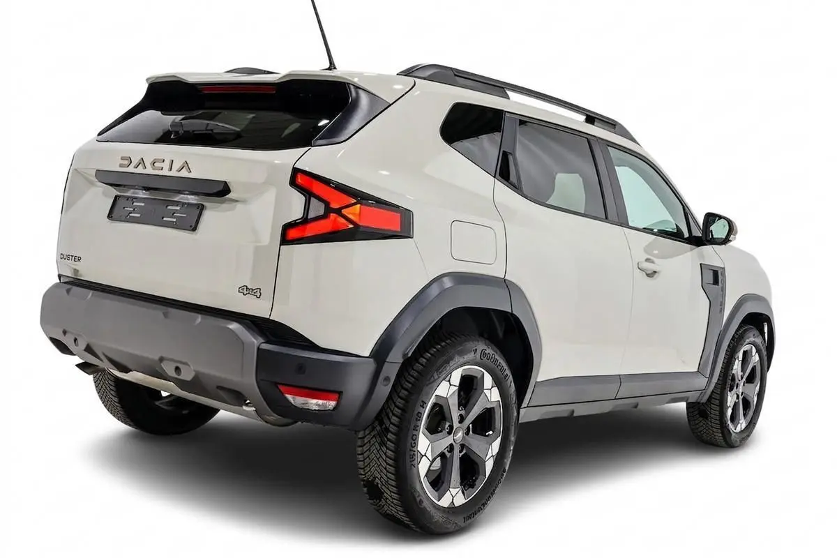 Vue 3/4 arrière droit du Dacia Duster 2024 couleur Sandstone avec jantes bi-ton et barres de toit noires.