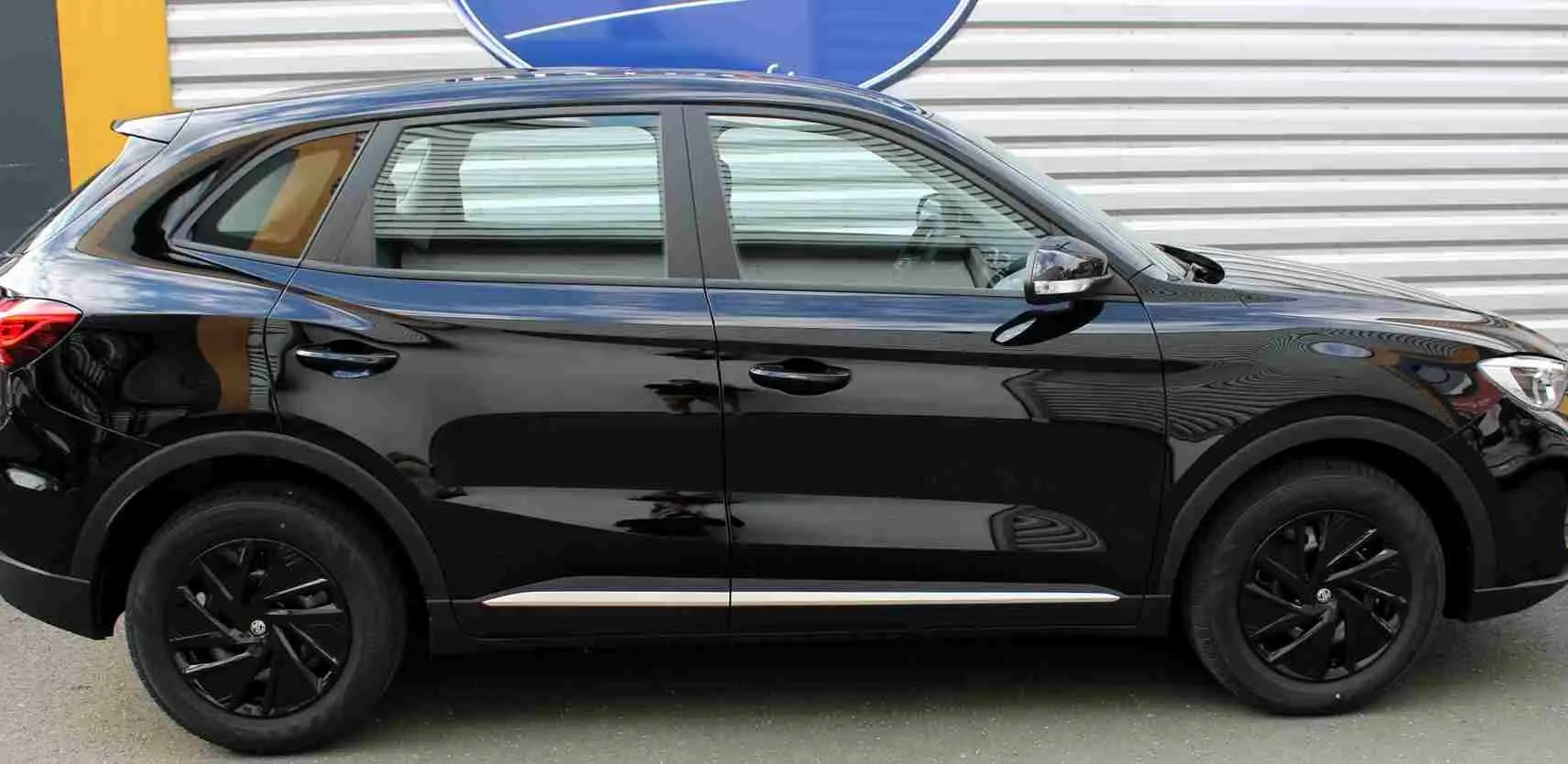 Vue intérieure côté gauche montrant les sièges avant en tissu gris et noir du MG ZS Pebble Black 2026.