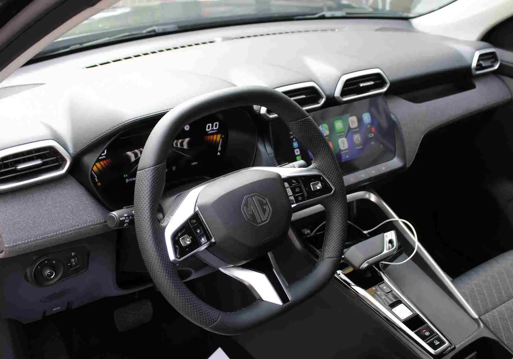 Vue frontale de l'intérieur du MG ZS 1.5L Hybrid+ 2026, avec volant multifonction et écran tactile central allumé.