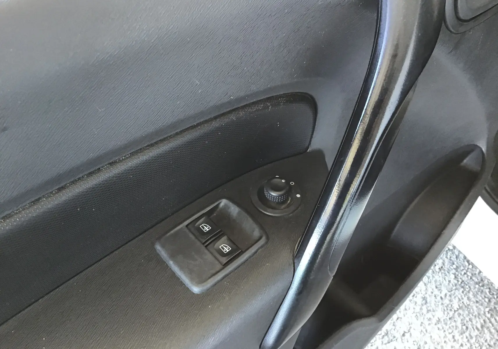 Détail de la porte avant gauche du Renault Kangoo blanc 2021, avec commandes électriques des vitres et réglage des rétroviseurs.