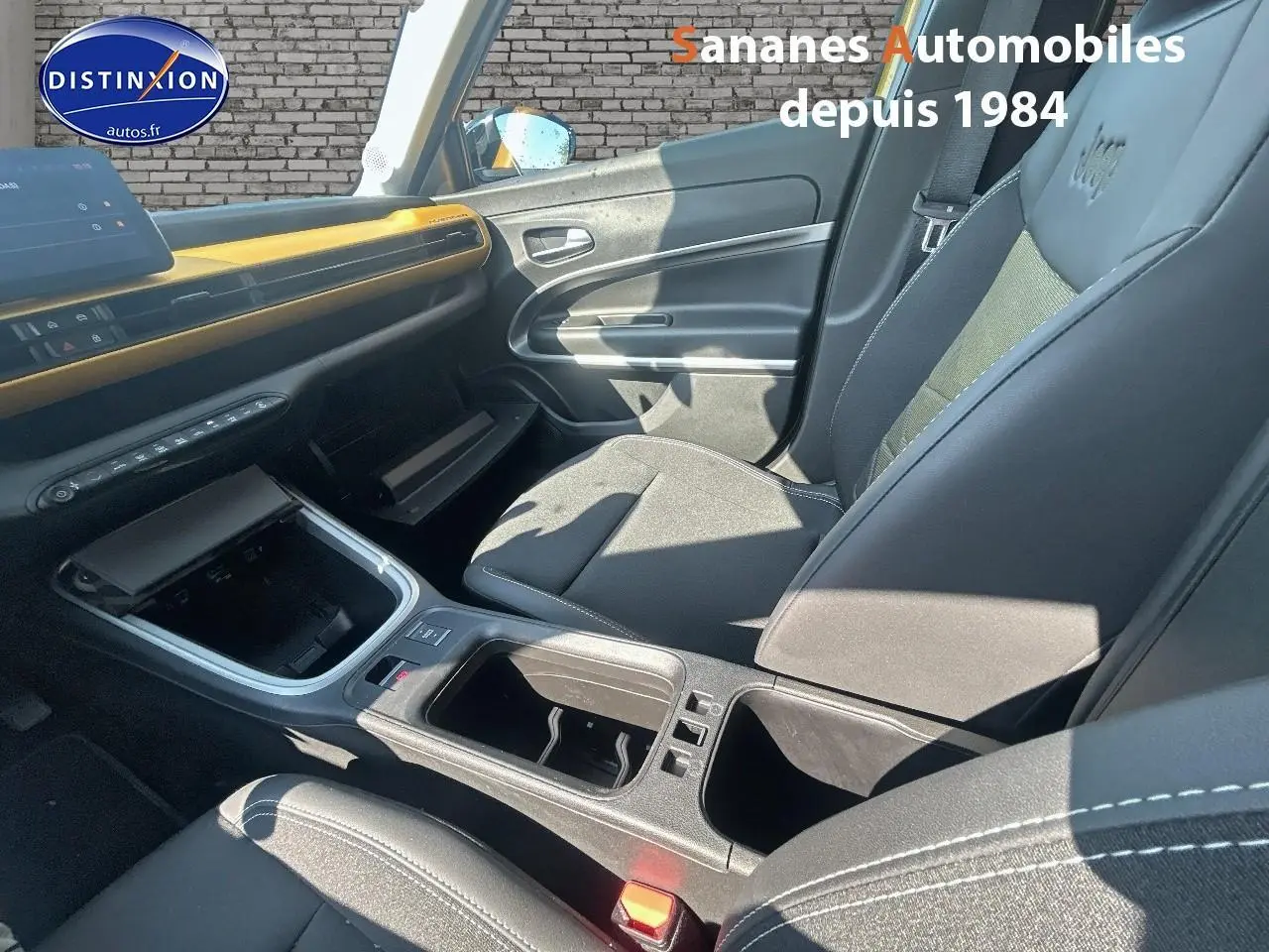 Intérieur avant droit du Jeep Avenger jaune foncé 2025 avec tableau de bord et sièges noirs, détails contrastants jaunes.