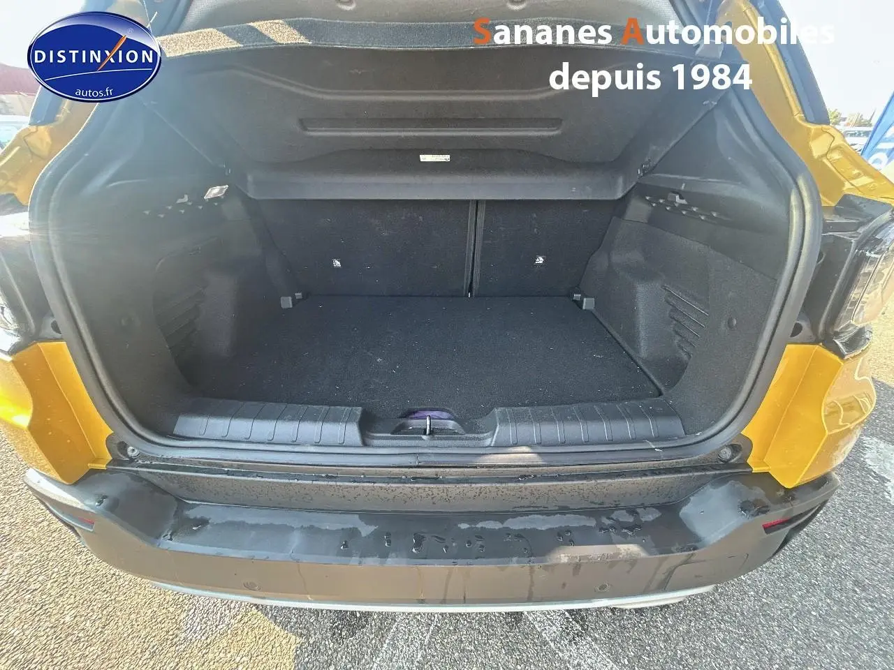Coffre ouvert vu de l'arrière d'un Jeep Avenger jaune foncé, montrant l'espace de chargement vide.