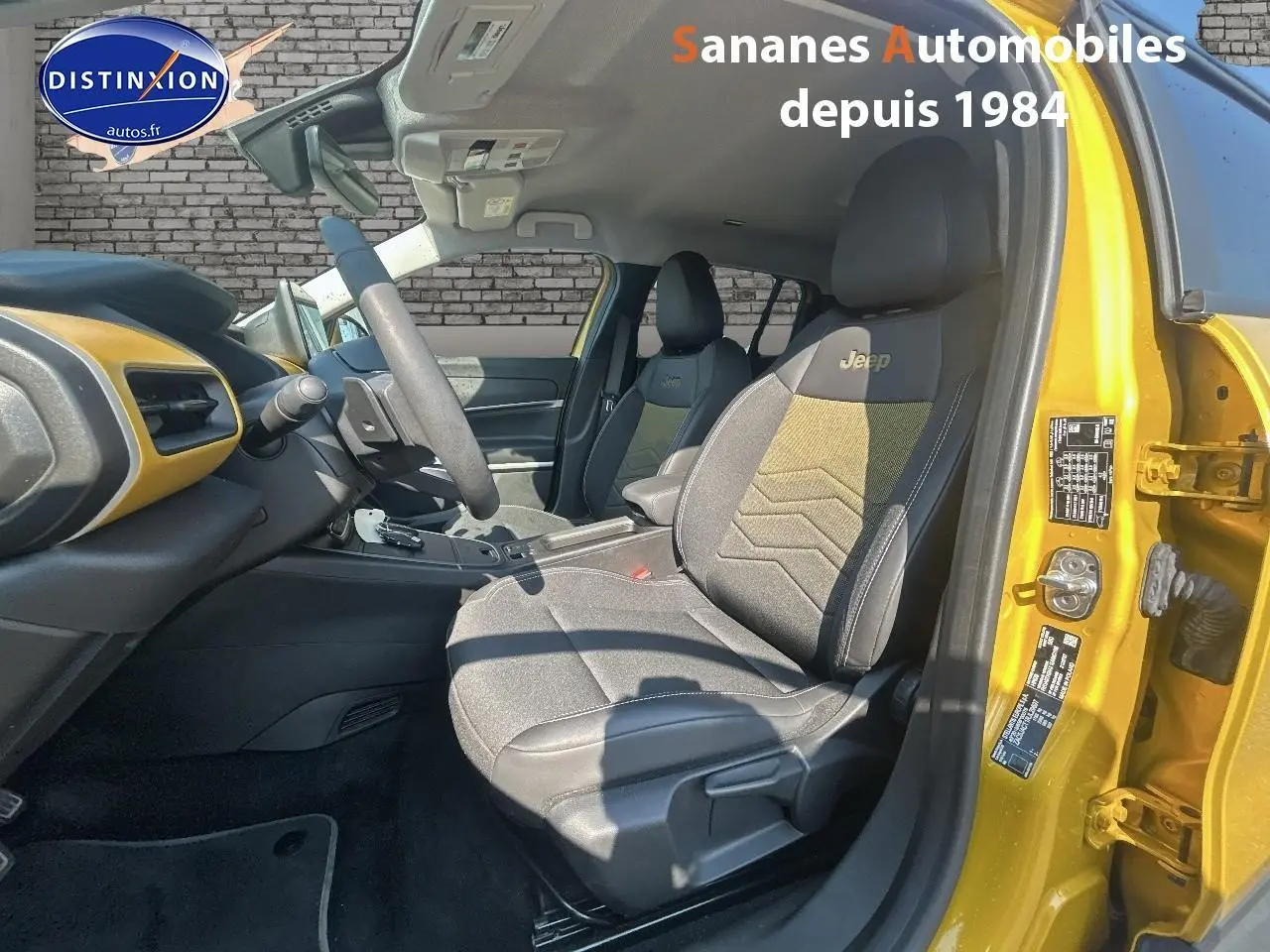 Vue intérieure côté conducteur du Jeep Avenger jaune foncé, mettant en valeur les sièges avec logo Jeep brodé.