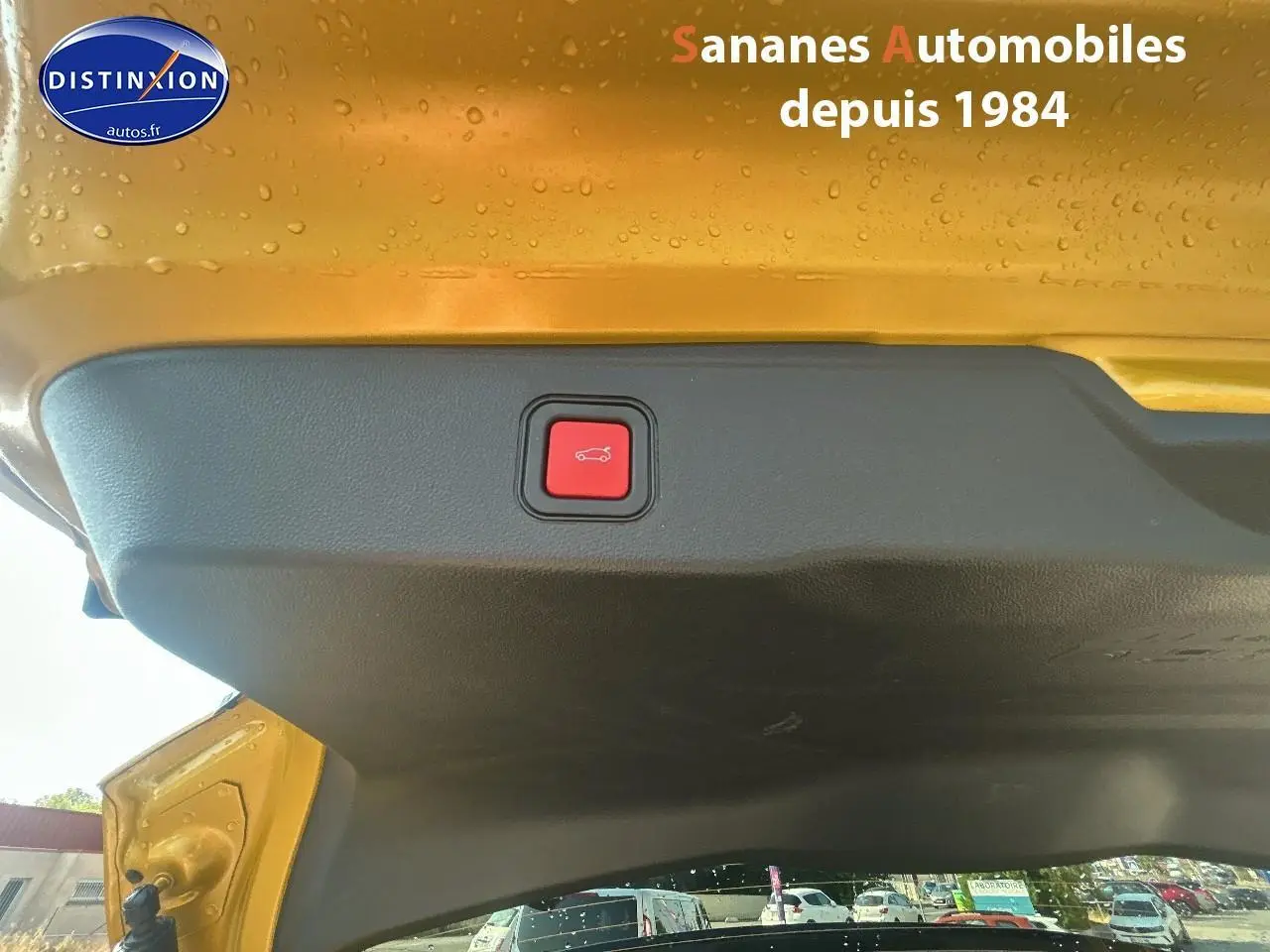 Bouton rouge d'ouverture électrique du hayon sur le coffre arrière jaune foncé d'un Jeep Avenger 2025.