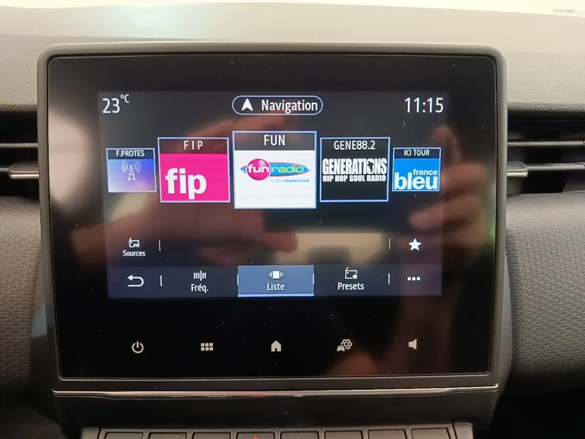 Écran tactile central de la Renault Clio Business E-TECH 140 blanc, affichant les stations radio et la navigation.