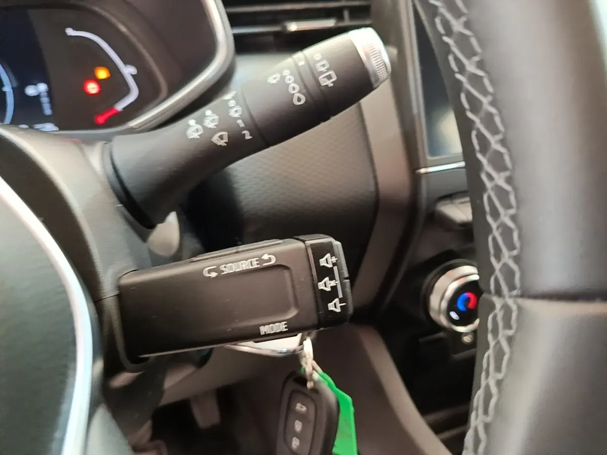 Gros plan sur la commande multifonctions et partie du volant en cuir synthétique de la Renault Clio Business E-TECH 140 blanche.
