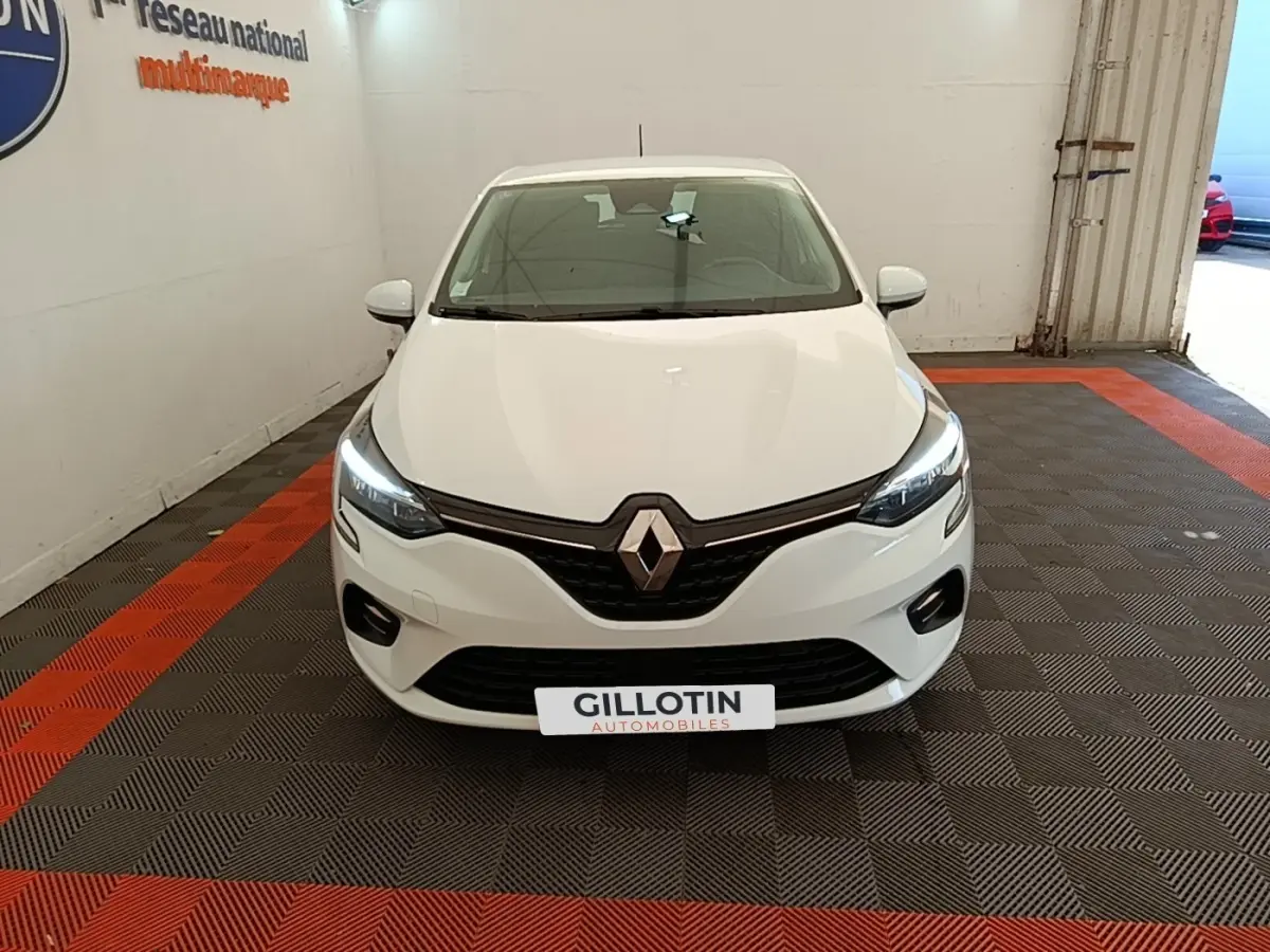 Renault Clio Business E-TECH 140 blanc vue de face, phares LED allumés dans un garage.