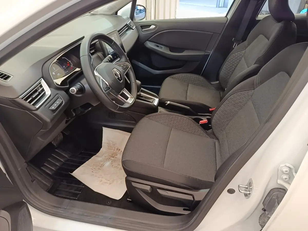 Vue intérieure côté conducteur de la Renault Clio Business E-TECH blanche, avec sièges gris et volant multifonctions en cuir synthétique.