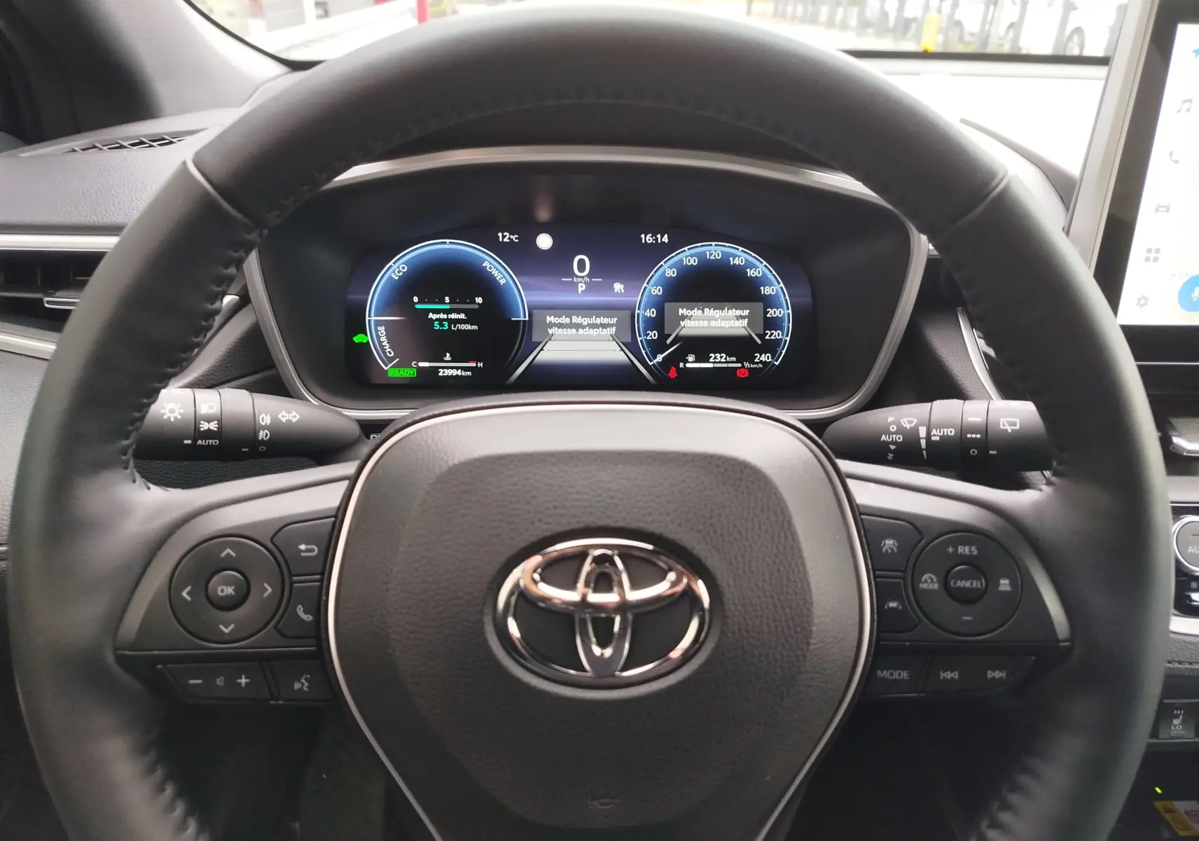 Vue centrée sur le volant noir et le tableau de bord numérique éclairé de la Toyota Corolla Cross Hybrid 2025.