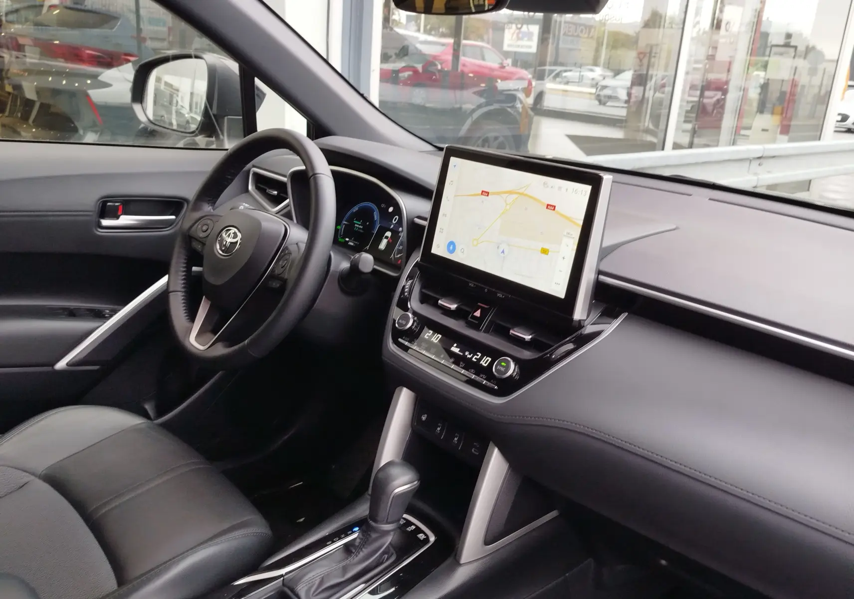 Vue intérieure côté conducteur de la Toyota Corolla Cross Hybrid 140 Luxury Limited avec écran tactile et sellerie noire.