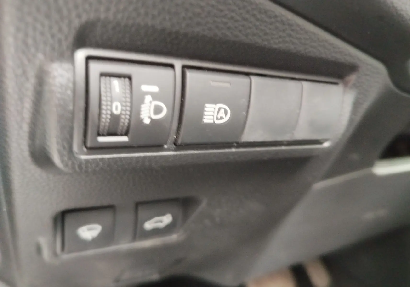 Gros plan sur les commandes d’éclairage et ouverture du coffre du Toyota Corolla Cross Hybrid 140 Luxury Limited 2025.
