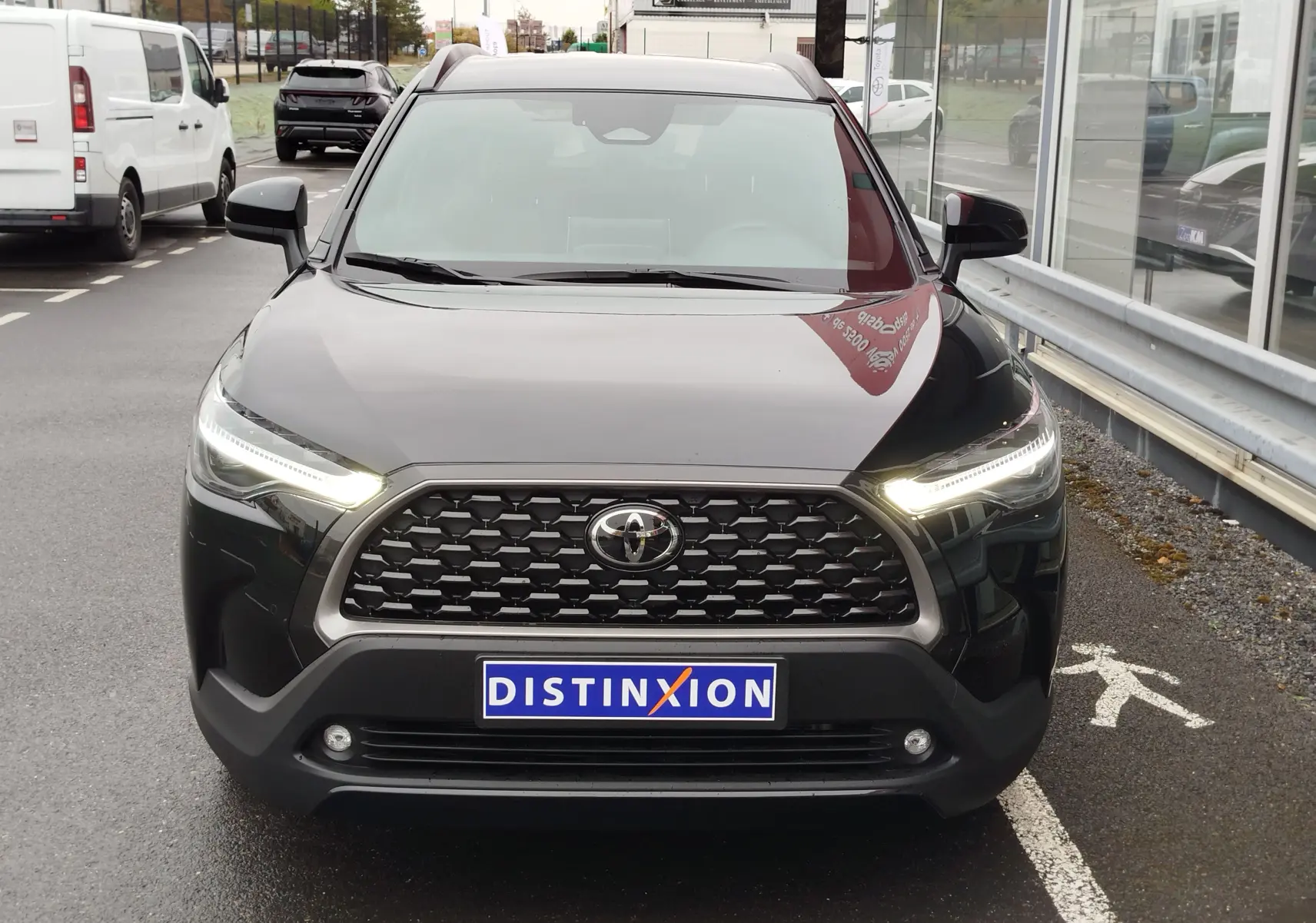Vue frontale d’un Toyota Corolla Cross Hybrid 140 Luxury Limited noir Attitude avec phares LED allumés et calandre hexagonale distinctive.