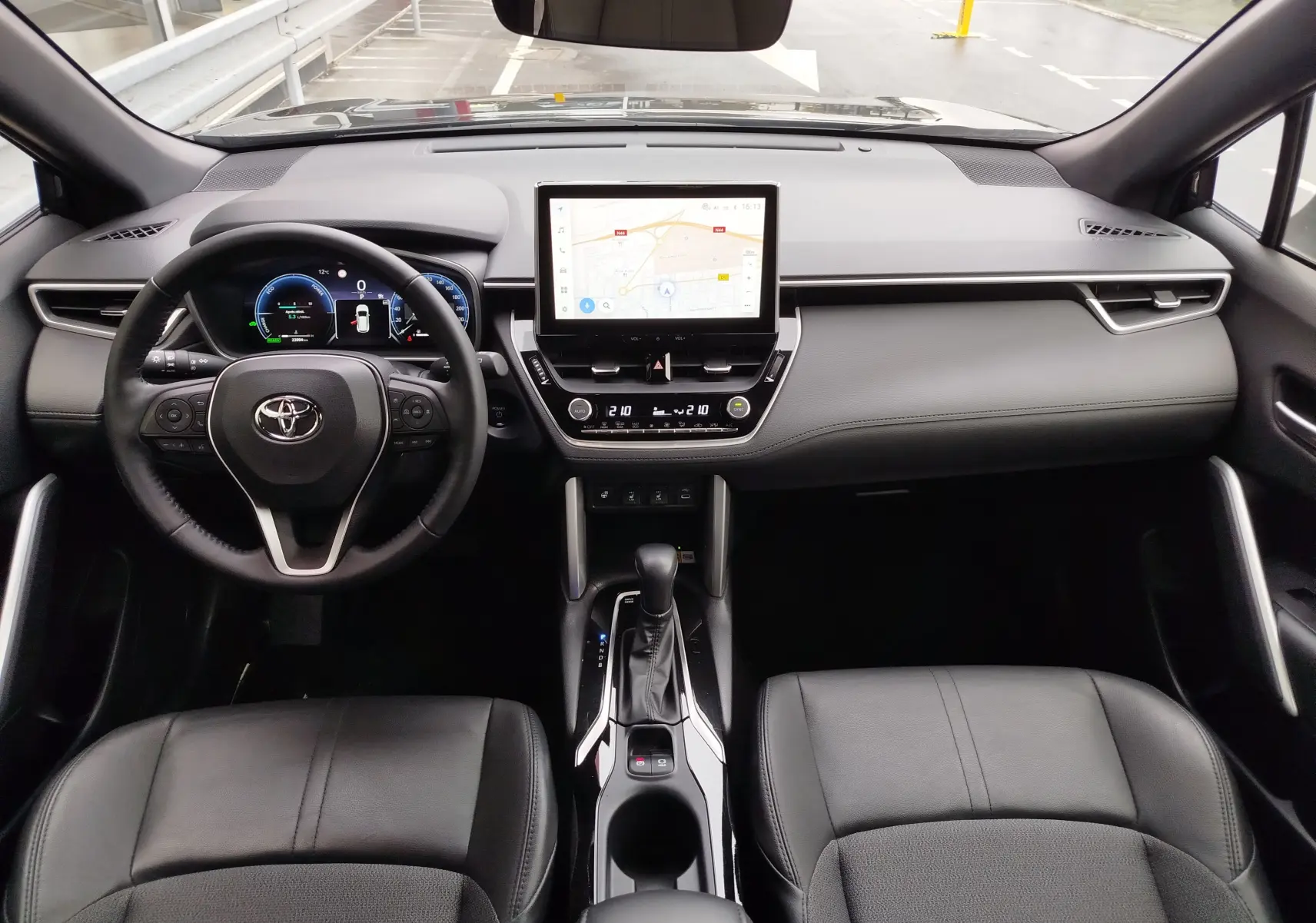 Vue intérieure avant de la Toyota Corolla Cross Hybrid 140 Luxury Limited 2025, tableau de bord noir avec écran tactile central et volant multifonction.