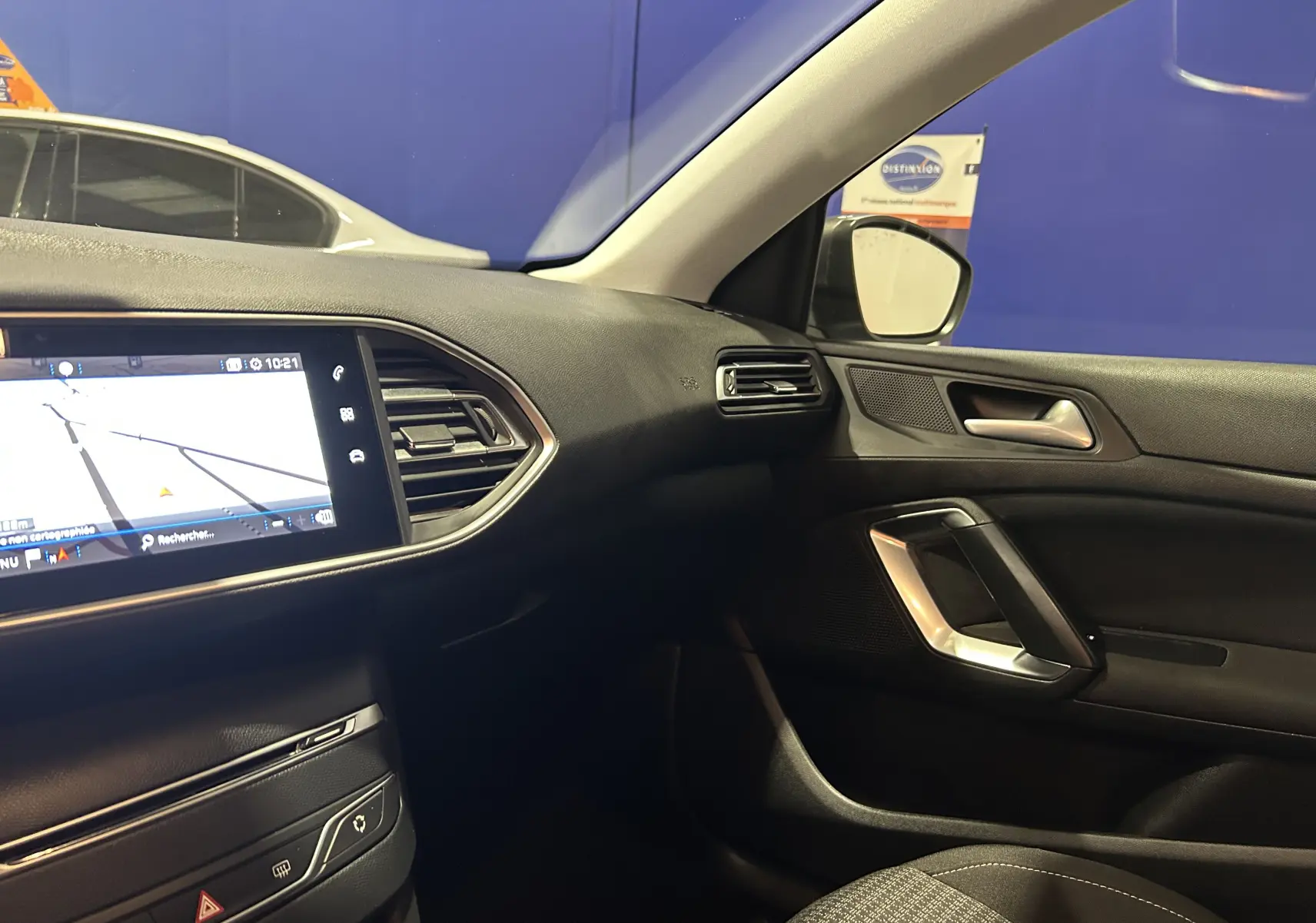 Intérieur côté passager d'une Peugeot 308 gris 2021, avec écran tactile et garnitures noires modernes.