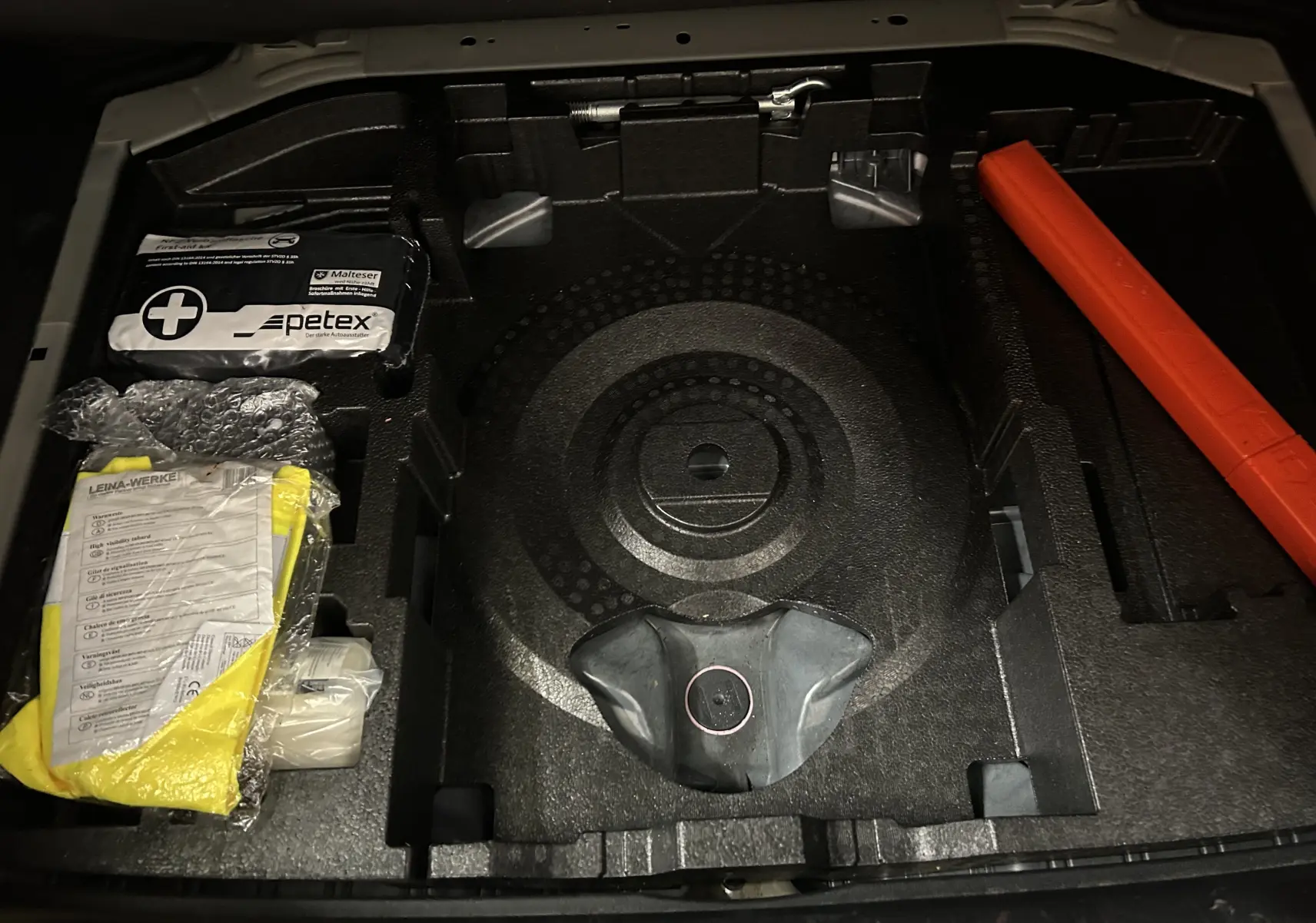 Coffre ouvert de la Peugeot 308 Active Pack gris 2021 montrant le rangement pour roue de secours et kit de sécurité.