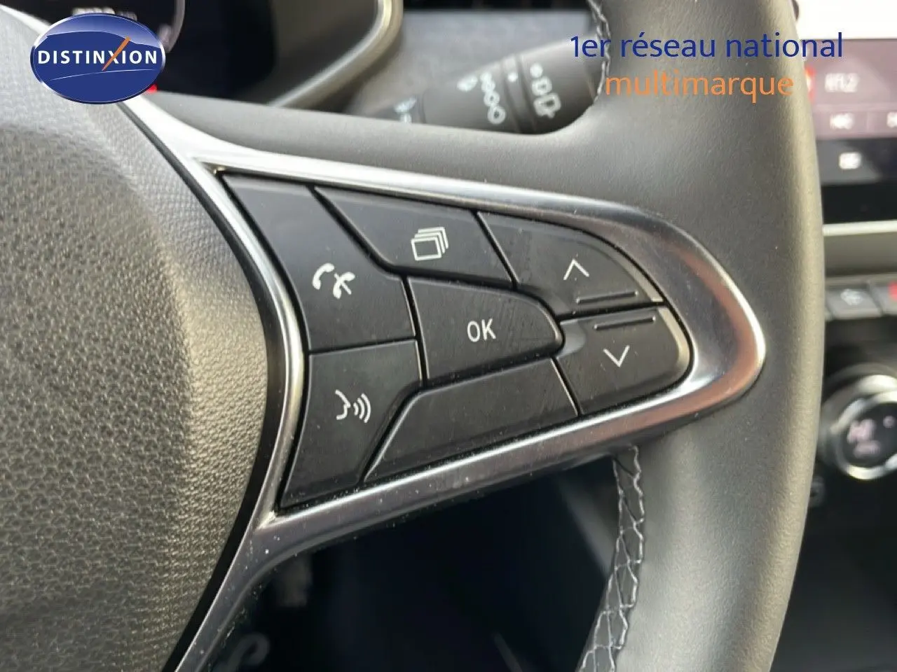 Gros plan sur les commandes multifonctions au volant côté droit de la Renault Clio 2025, finition rouge Désir Métal.