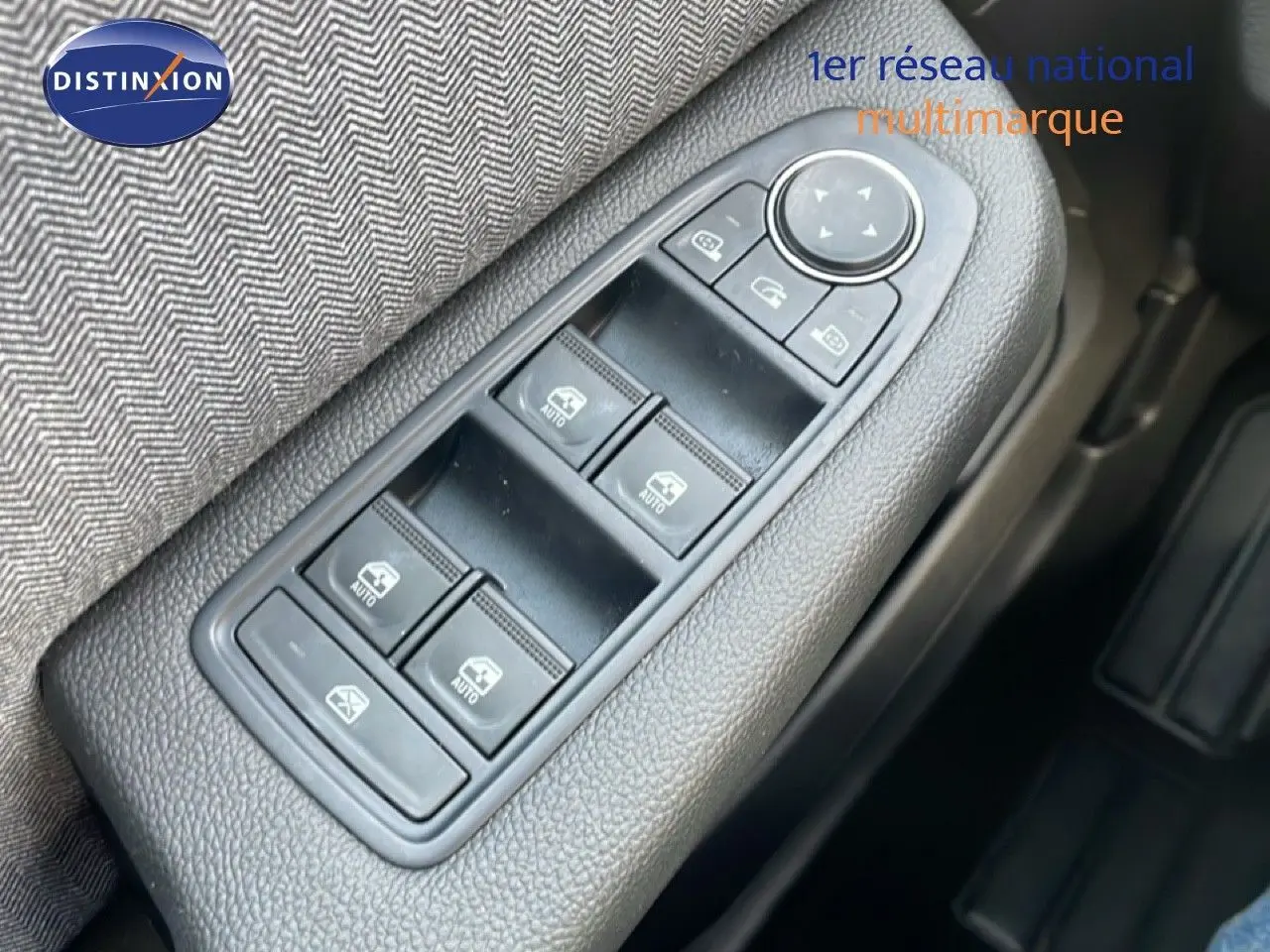 Gros plan sur les commandes des vitres électriques côté conducteur dans l’habitacle d’une Renault Clio rouge Désir Métal 2025.