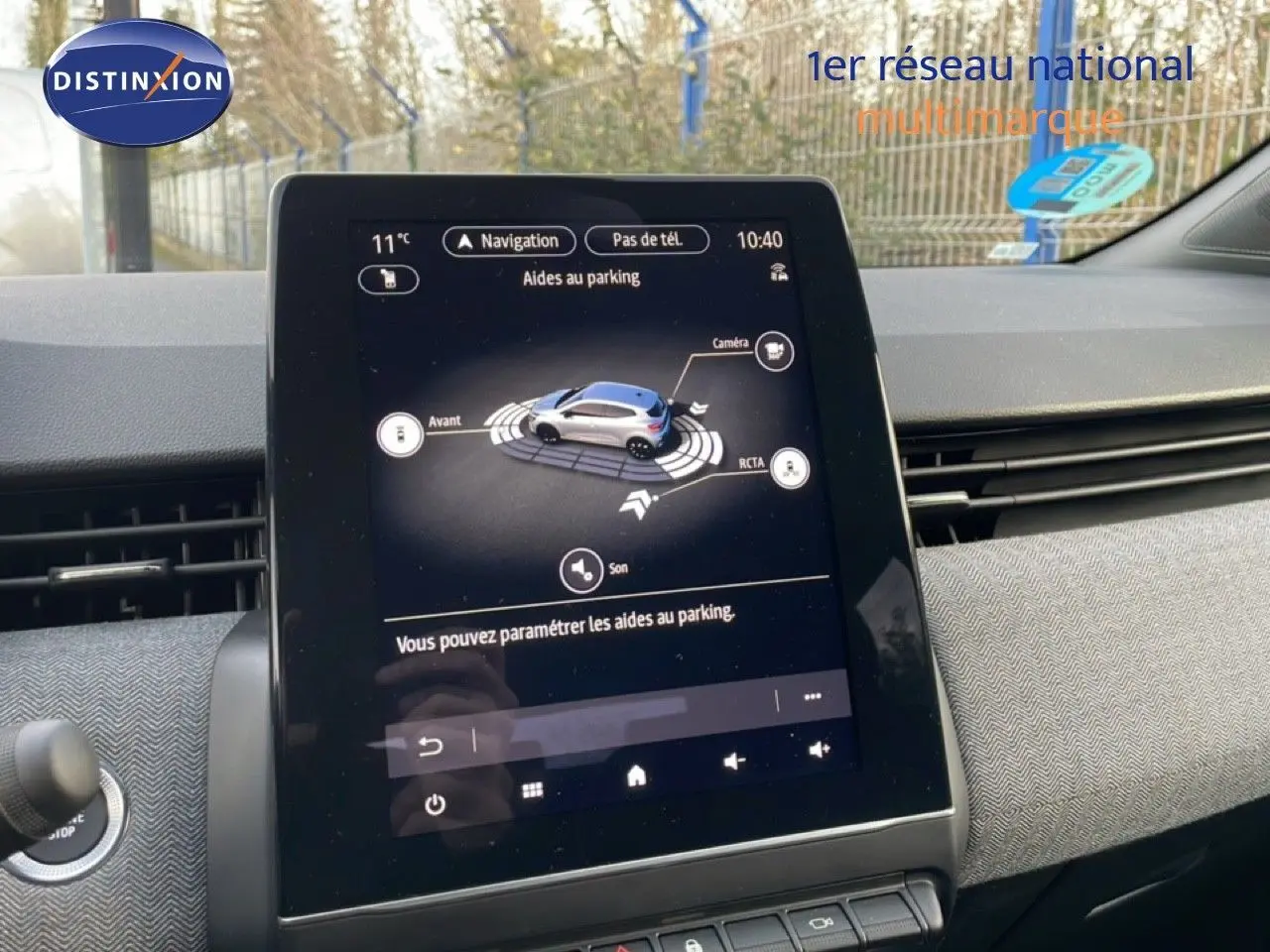 Écran tactile central affichant l'aide au parking dans l'habitacle d'une Renault Clio rouge, vue de face.