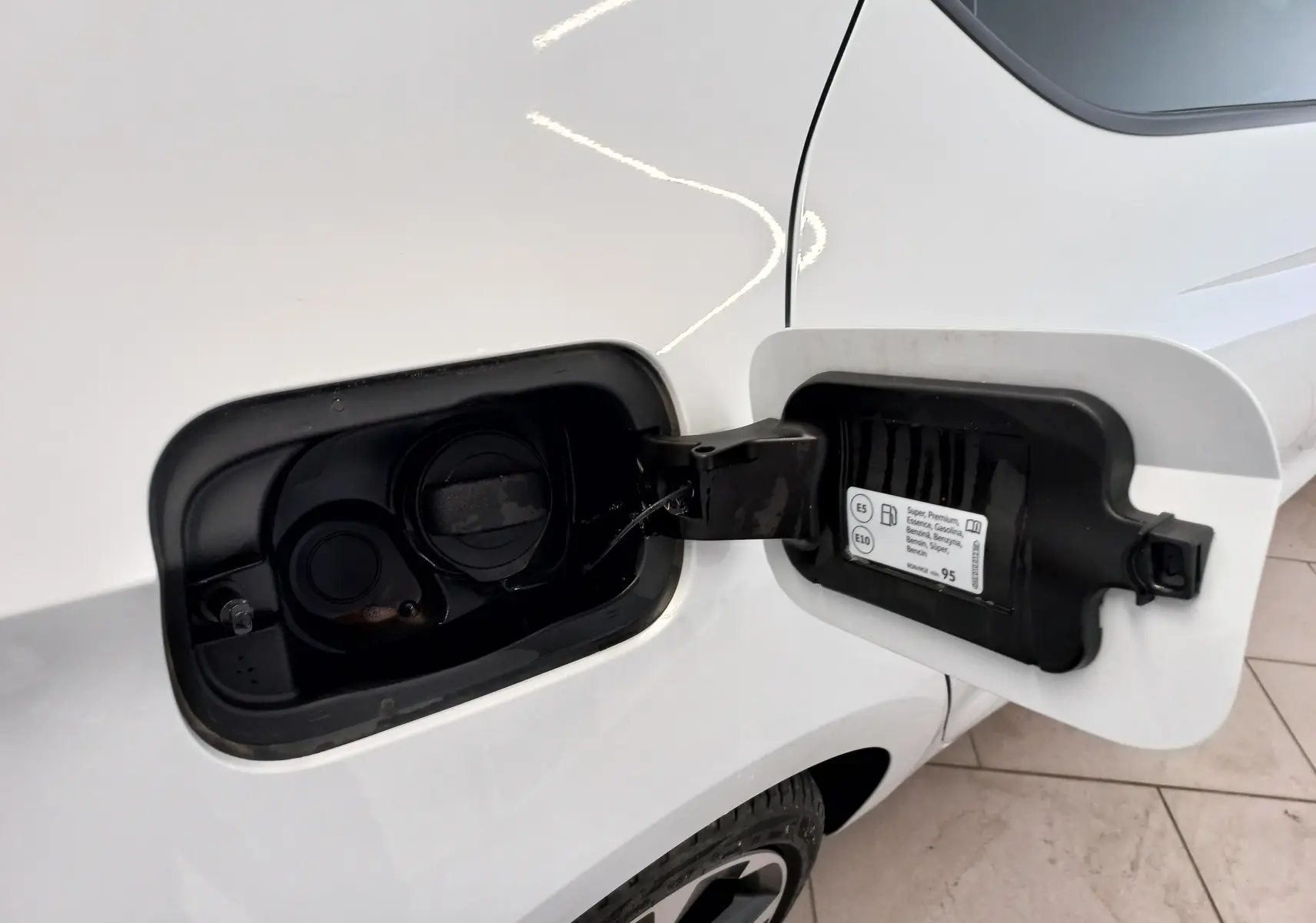Gros plan sur la trappe à carburant côté gauche d'une CUPRA Leon blanc Nevada 2025 avec bouchon essence ouvert.