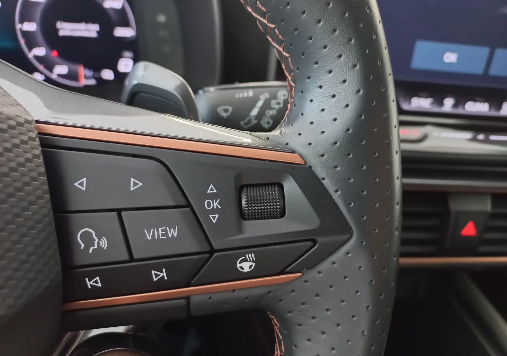 Gros plan sur les commandes à droite du volant perforé avec surpiqûres cuivrées de la CUPRA Leon 2025.
