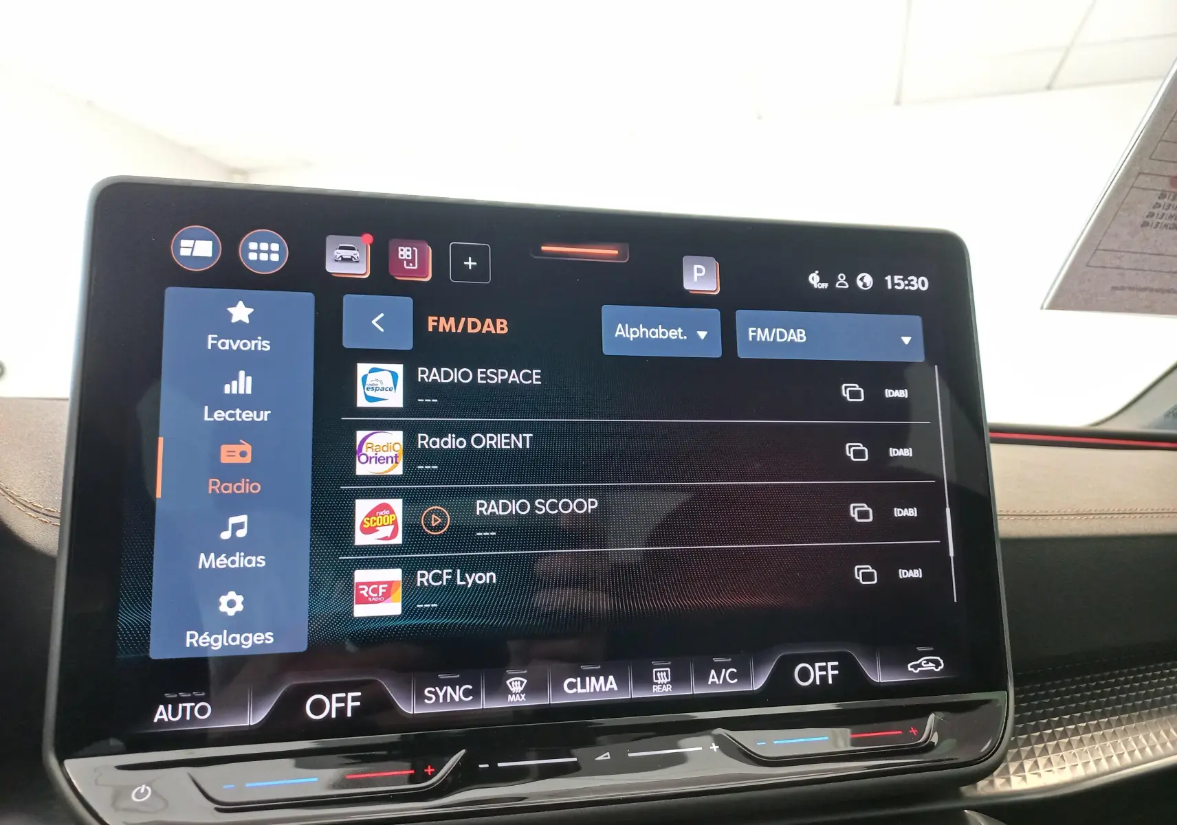 Écran tactile central du tableau de bord du CUPRA Leon blanc Nevada, affichant les options radio FM/DAB.