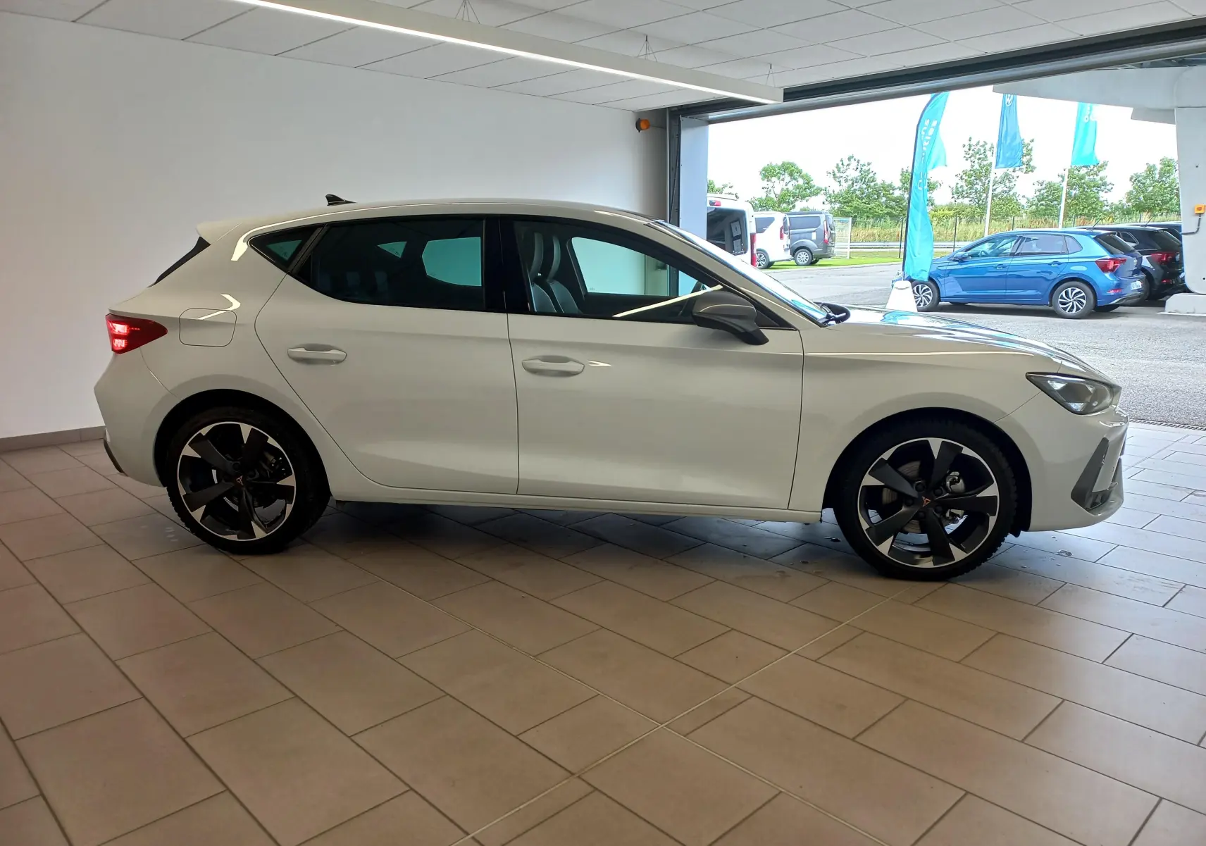 Vue de profil côté gauche d'une CUPRA Leon Phase 2 blanche Nevada avec jantes noires et détails sportifs visibles.
