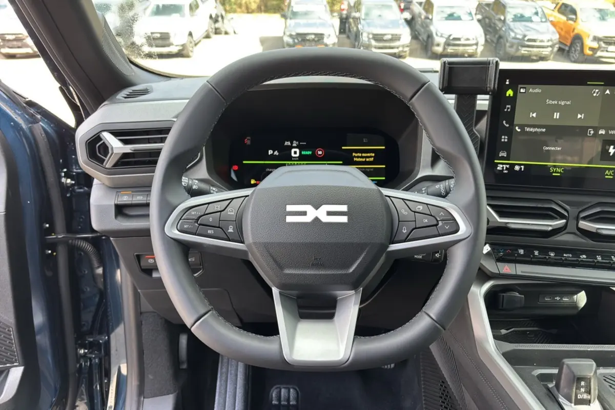 Vue intérieure centrée sur le volant cuir et le tableau de bord digital du Dacia Bigster Hybrid 155 en bleu indigo.