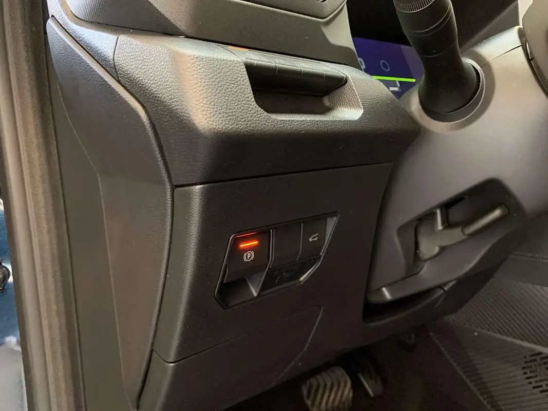 Détail intérieur côté conducteur du Dacia Bigster Hybrid 155 Journey Plus montrant le bouton de frein à main électrique allumé.