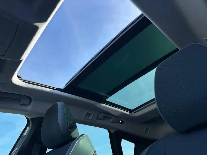 Vue intérieure du toit ouvrant panoramique et des appuie-têtes avant du Citroën C5 Aircross 2026, ciel bleu visible.