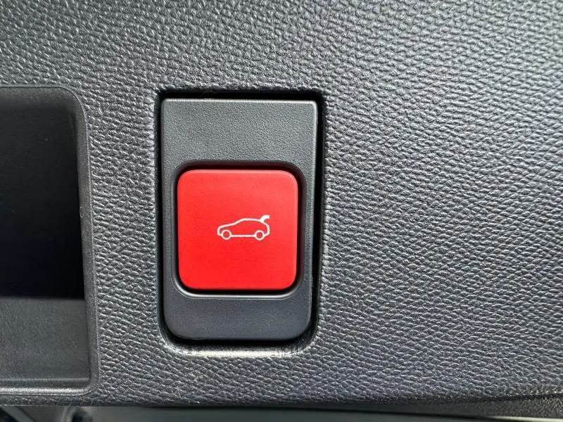 Bouton rouge d'ouverture électrique du coffre sur tableau de bord noir texturé d'une Citroën C5 Aircross 2026 hybride.
