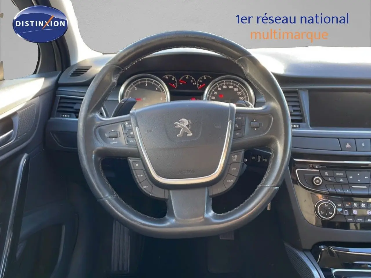 Vue intérieure centrée sur le volant noir de la Peugeot 508 blanche de 2012 avec tableau de bord et commandes visibles