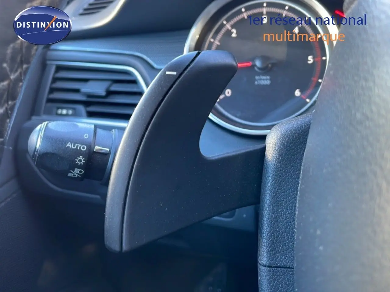 Gros plan sur la commande de palette de boîte automatique noire à gauche du volant dans l'habitacle d'une Peugeot 508 blanche de 2012.