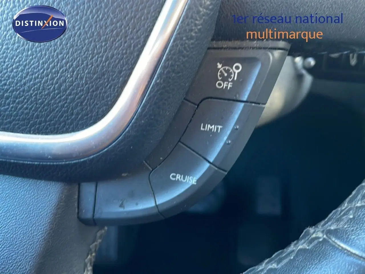 Gros plan sur les commandes de régulateur de vitesse au volant noir de la Peugeot 508 blanche de 2012.