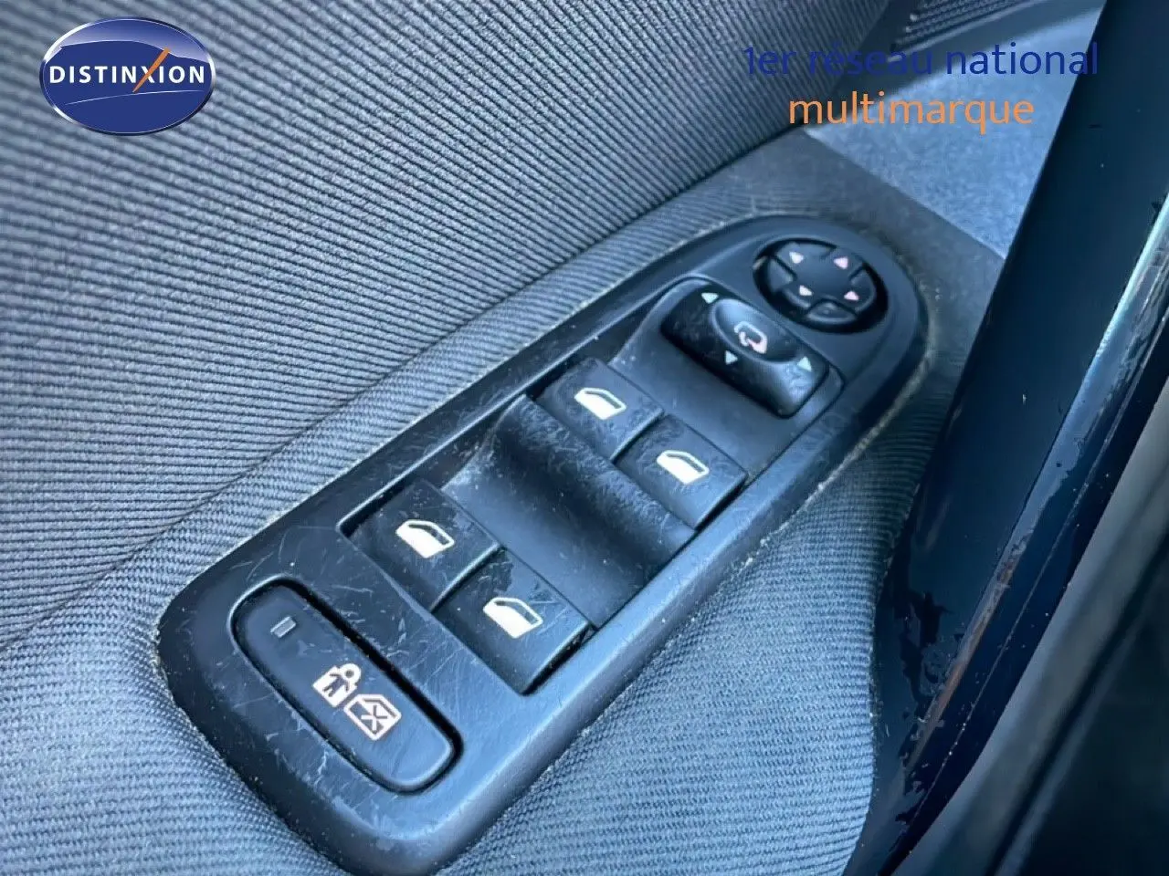 Gros plan sur les commandes des vitres électriques côté conducteur d'une Peugeot 508 blanche de 2012.