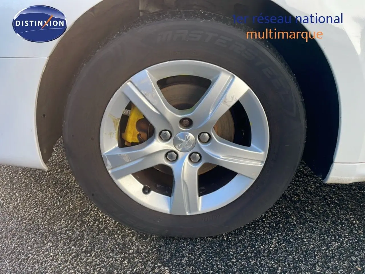 Gros plan sur la roue avant gauche d'une Peugeot 508 blanche avec étrier de frein jaune visible.