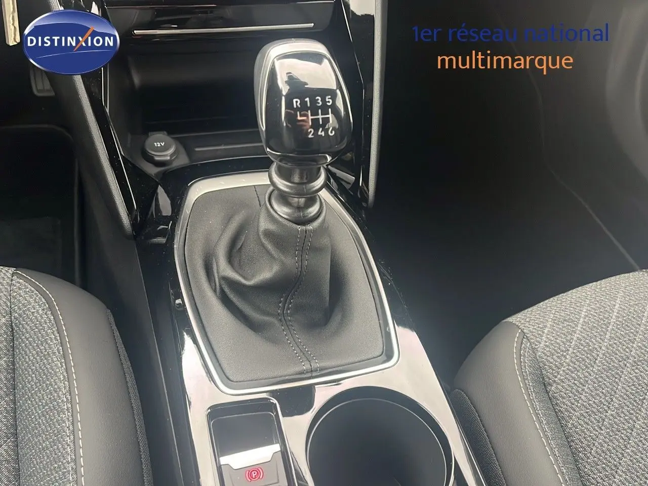 Le levier de vitesses manuel de la Peugeot 2008 2025, avec console centrale noire et sièges gris partiellement visibles.