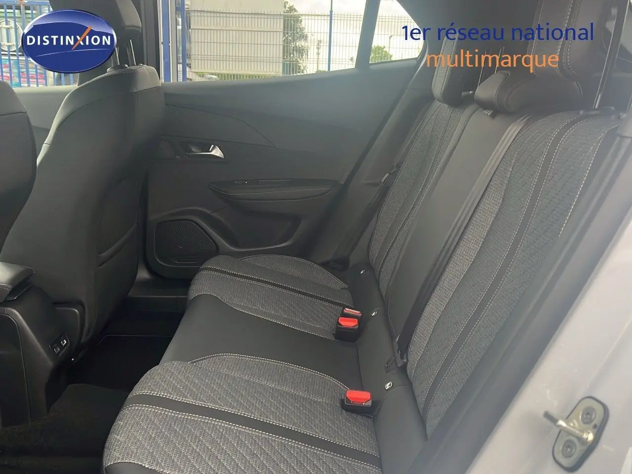 Vue latérale droite de l'habitacle arrière d'une Peugeot 2008 blanche, sièges tissu noir et gris avec surpiqûres blanches.