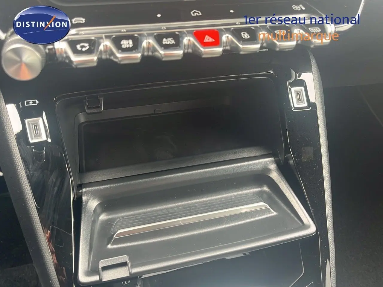 Gros plan sur la console centrale noire du Peugeot 2008 2025, montrant les boutons de commande et un rangement ouvert.