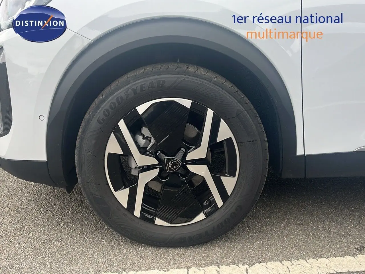 Gros plan sur la roue avant gauche d'un Peugeot 2008 blanc Okenite avec jante alliage noire et argentée.