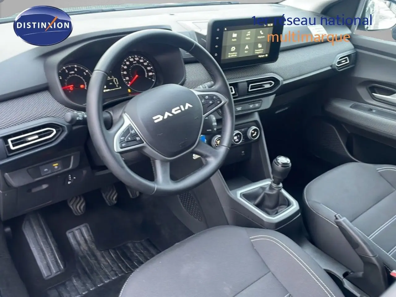 Vue intérieure côté conducteur du Dacia Jogger 2025, tableau de bord noir avec écran tactile et levier de vitesses manuel.