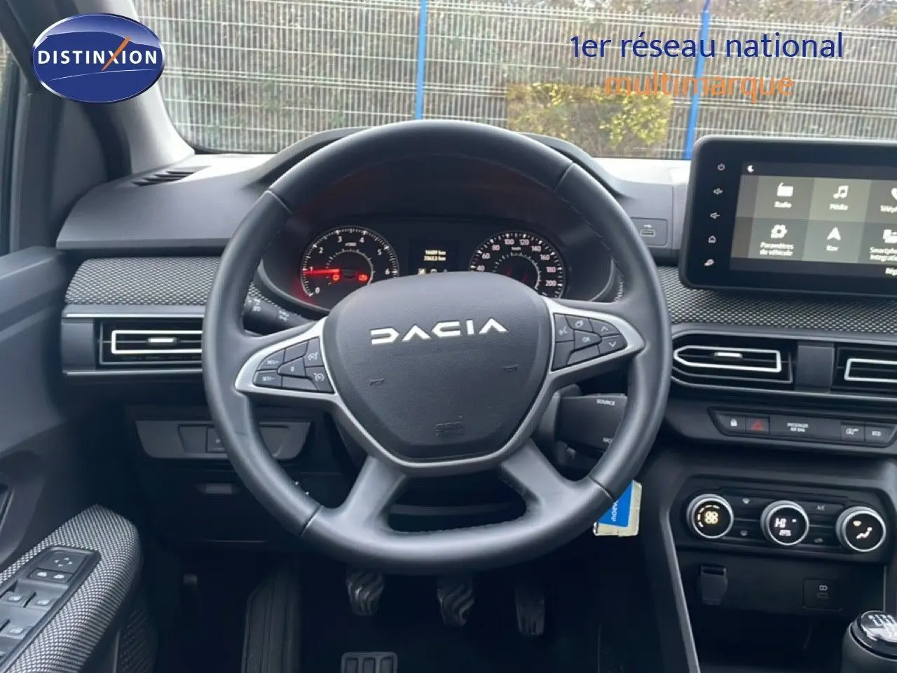 Vue intérieure centrée sur le volant DACIA d’un Jogger 2025, avec tableau de bord et écran tactile visibles.