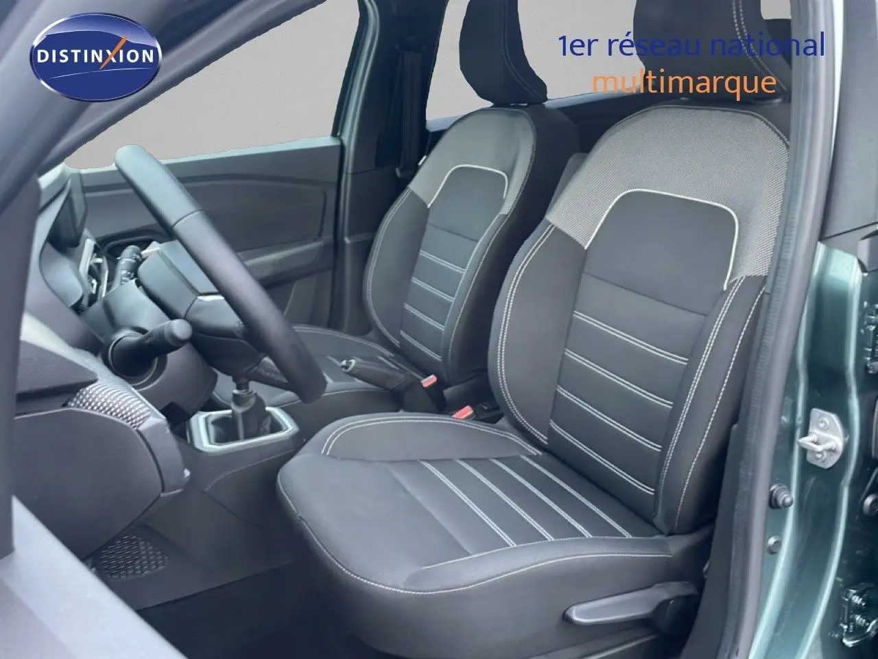 Vue intérieure côté conducteur du Dacia Jogger 2025 vert cèdre métal, montrant les sièges noirs et la boîte manuelle.