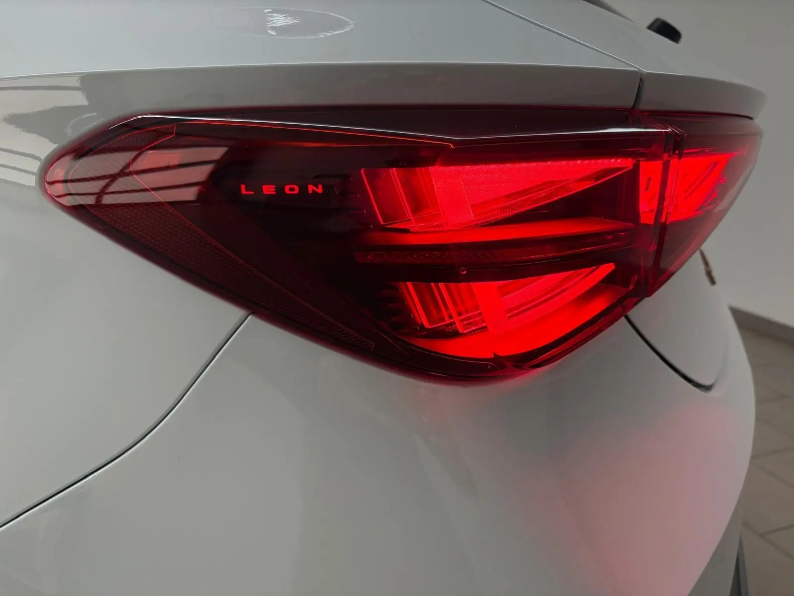 Gros plan sur le feu arrière droit rouge de la CUPRA Leon blanc Nevada avec inscription LEON lumineuse.