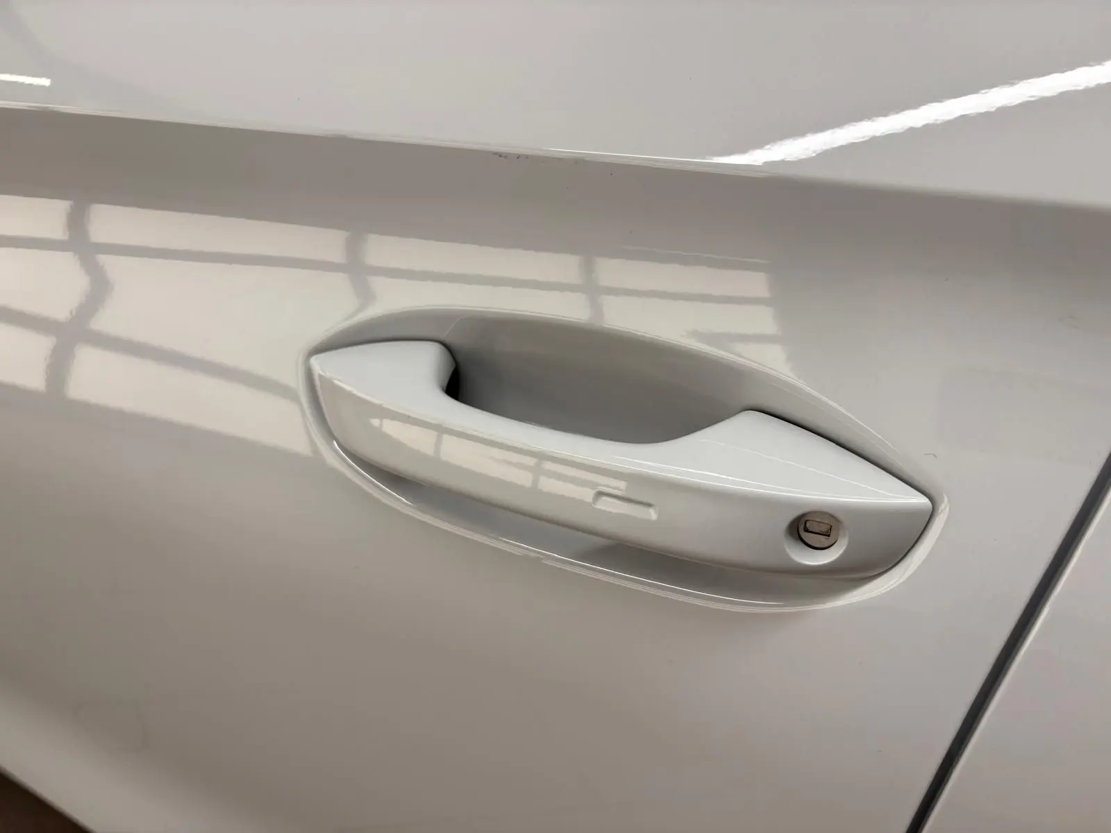 Poignée de porte côté gauche de la CUPRA Leon Phase 2 2025 en blanc Nevada métallisé, avec serrure visible.