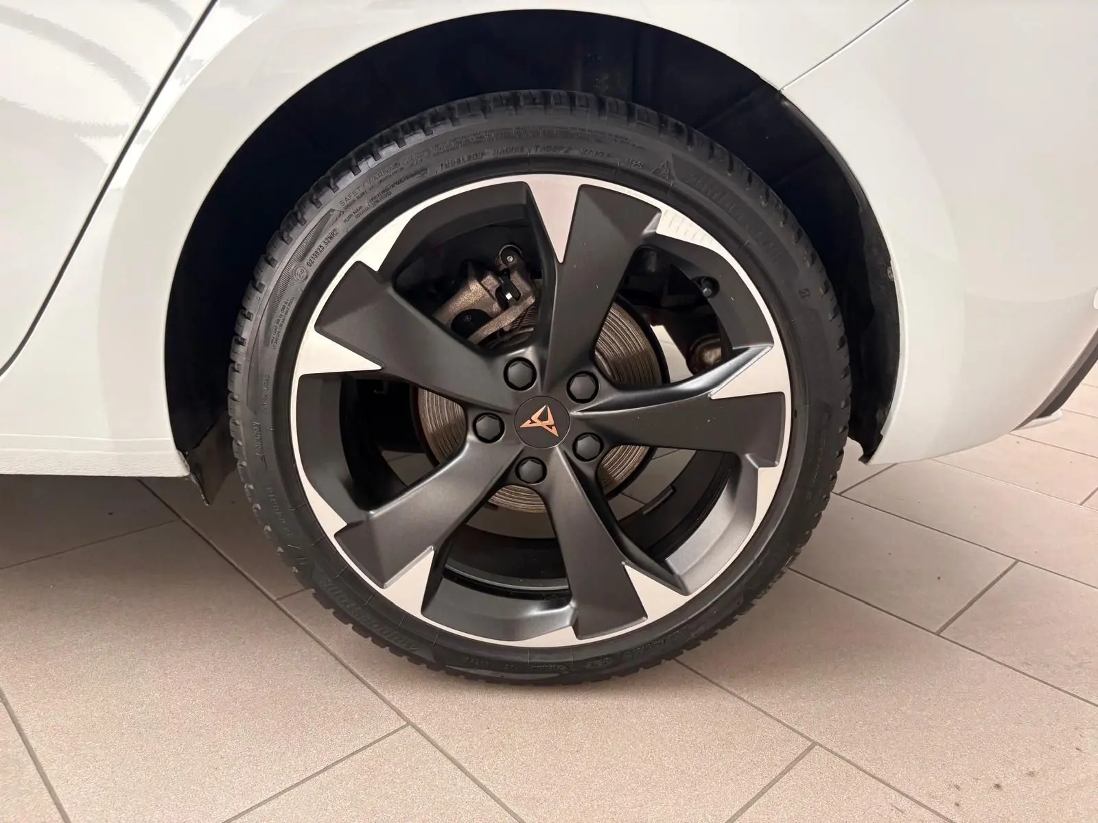 Gros plan sur la roue arrière droite d'une CUPRA Leon blanc Nevada avec jante alliage bicolore et logo CUPRA central.