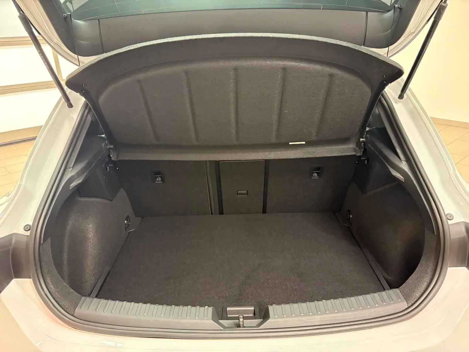 Coffre ouvert vu de l'arrière d'une CUPRA Leon Phase 2 blanc Nevada avec intérieur de coffre noir et tapis plat.