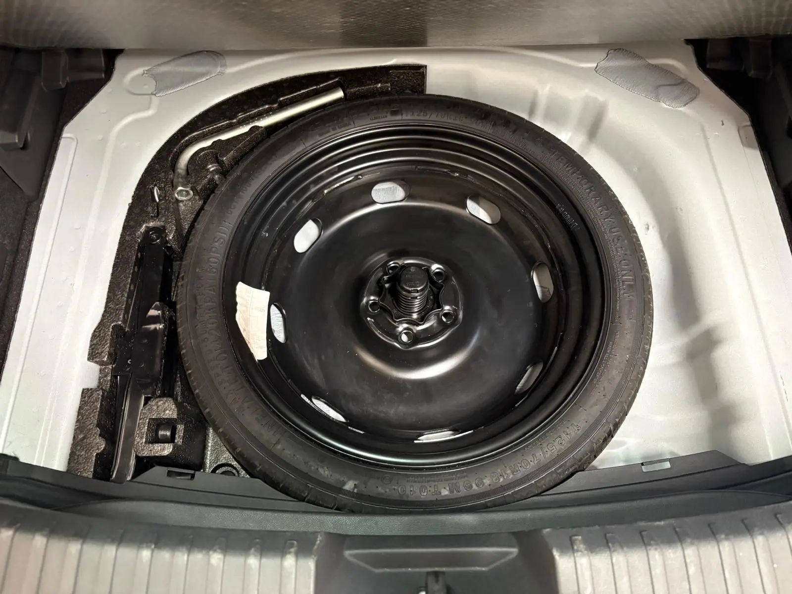 Gros plan sur la roue de secours noire dans le coffre blanc du CUPRA Leon Phase 2 2025.