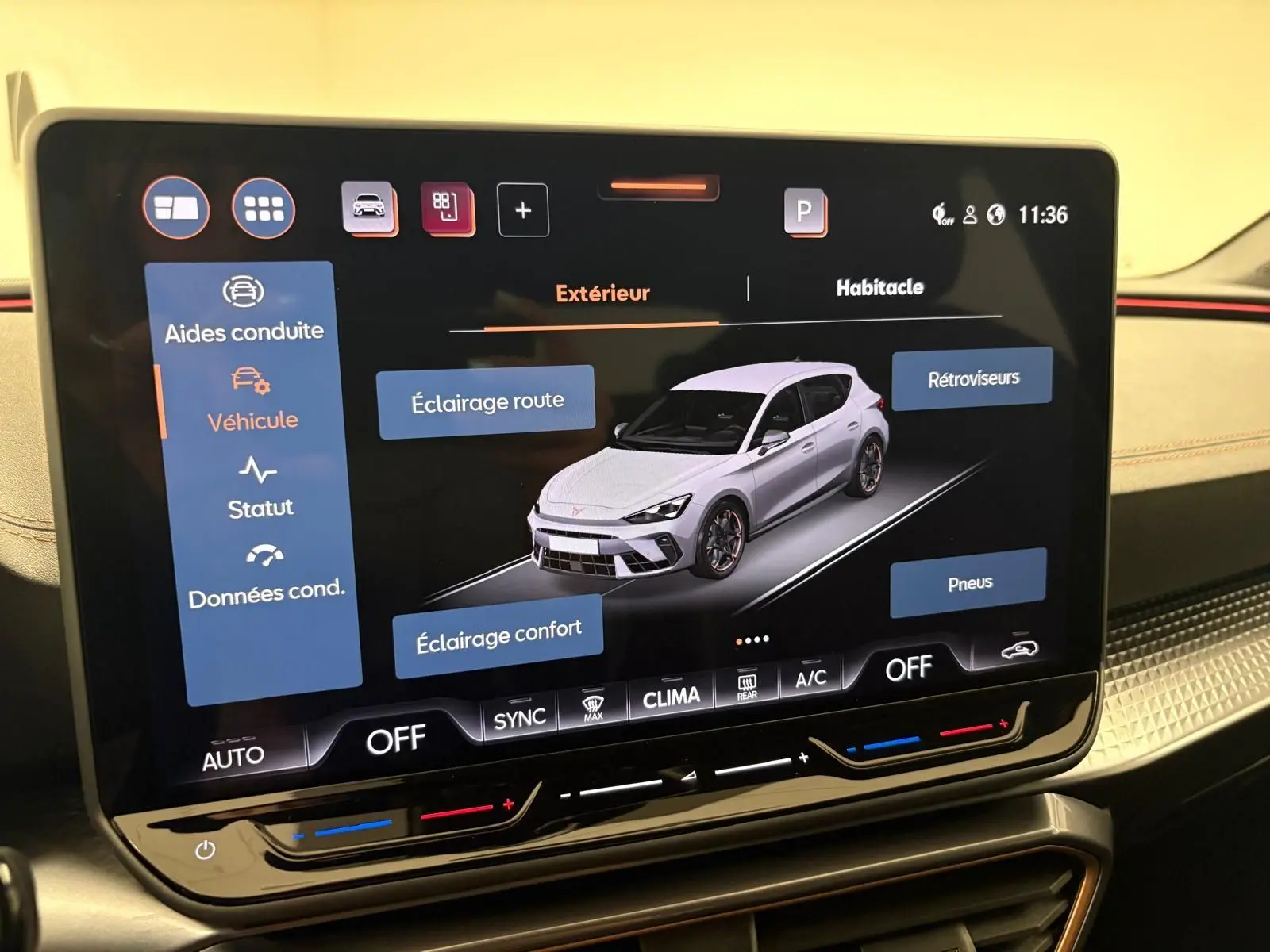 Écran tactile intérieur montrant une vue 3/4 avant d'une CUPRA Leon blanc Nevada avec options d'éclairage et pneus.