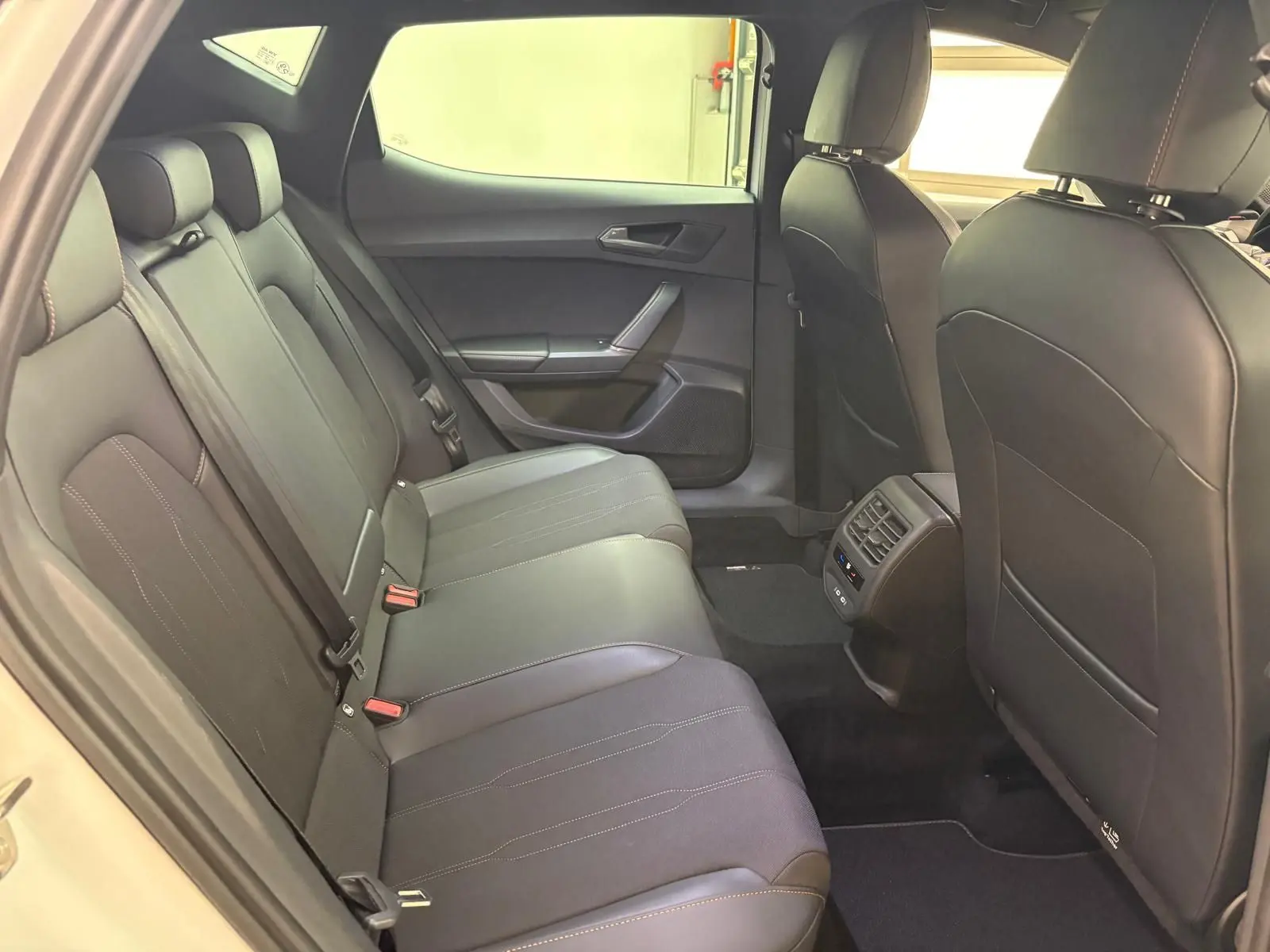 Vue intérieure arrière de la CUPRA Leon Phase 2 avec sièges noirs et détails de coutures contrastées visibles.